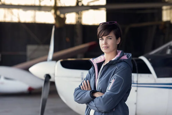 Mooie Vrouw Poseren Hangar Met Gekruiste Armen Lichte Vliegtuigen Achtergrond — Stockfoto