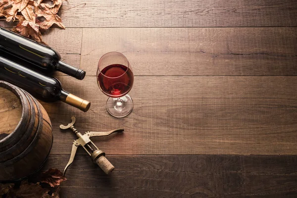 Mükemmel kırmızı şarap şişeleri, bardağı, varil ve tirbuşon bir rustik ahşap tablo: geleneksel şarap yapımı ve şarap tadımı kavramı