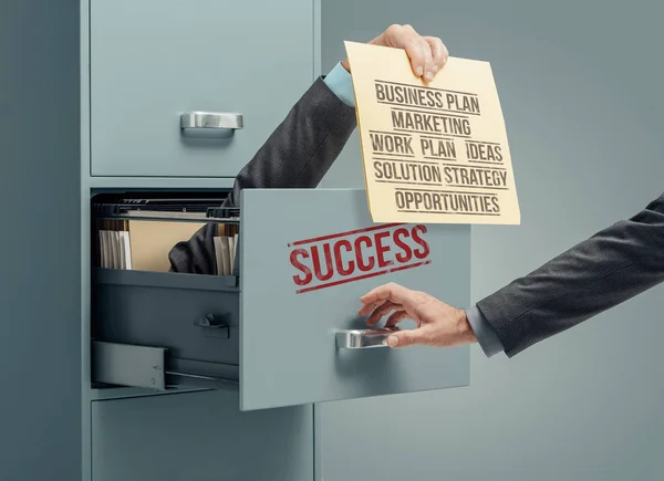 Businessman inside a filing cabinet giving a file with a successful business strategy to an office clerk