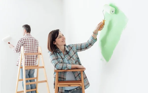 Couple renovating their home and painting walls together with paint rollers — Stock Image Couple Renovating Home Painting Walls Together Paint Rollers Royalty Free Stock Photos