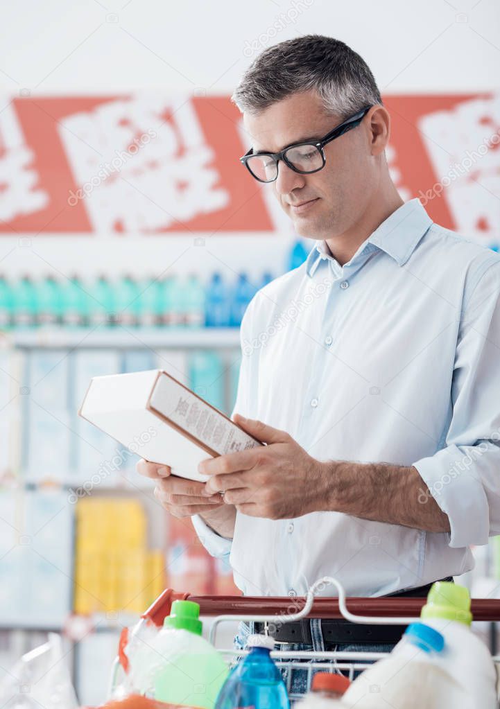 Man doing grocery shopping at the supermarket and reading a food label on a box, shopping and nutrition concept