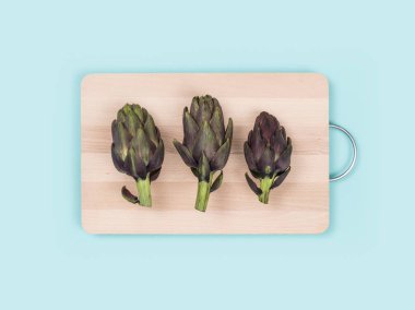 Fresh artichokes on a chopping board, food preparation and healthy eating concept clipart