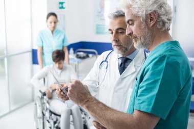 Kendine güvenen profesyonel doktorlar hastanın x-ray ve kadın arka planda bir hemşire yardımıyla tekerlekli sandalye üzerinde incelenmesi