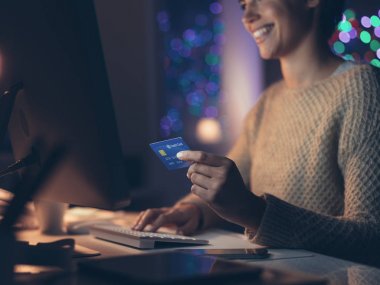 Onun bilgisayar ile gece geç saatte bağlanma ve online kredi kartı ile alışveriş yaparken gülümseyen genç kadın