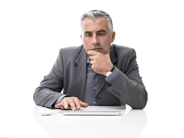 忧郁的生意人坐在办公桌前和电脑一起工作 他正在用手在下巴思考 — 图库照片