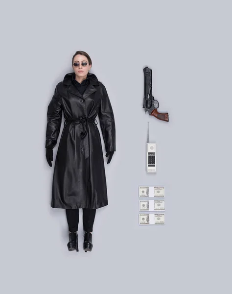 Lifelike female spy agent human doll with leather coat, gun and accessories, flat lay