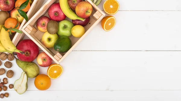 Fresh tasty fruit in a crate and wooden table top view, healthy food concept