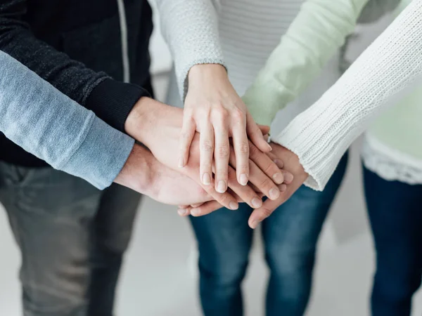 Unga människor stapla händerna tillsammans — Stockfoto