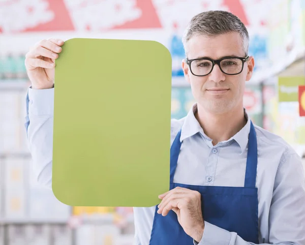 Impiegato del supermercato che detiene segno in bianco — Foto Stock