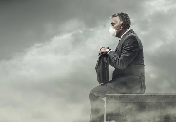 Businessman sitting on rooftop in polluted city — Stock Photo, Image