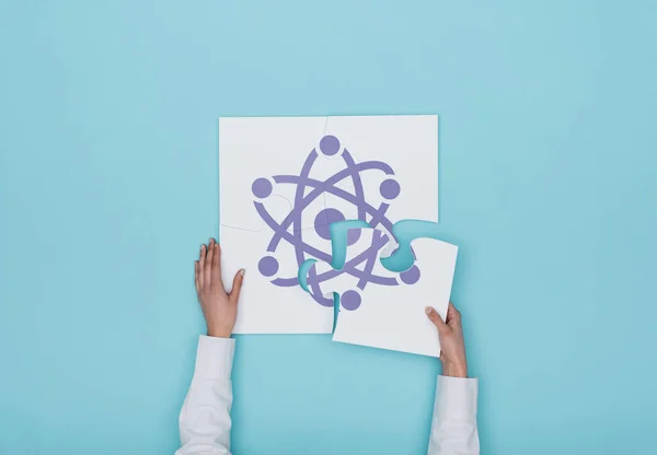 Woman completing puzzle with atom icon — Stock Photo, Image