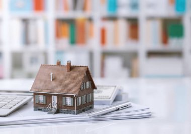 Model ev, hesap makinesi, nakit para ve evrak bir masa üzerine: gayrimenkul, ev kredisi ve yatırımlar kavramı