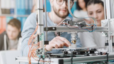 Erkek ve dişi mühendislik öğrencileri bir 3d printerlere harcama maddeler laboratuarı, teknoloji ve öğrenme kavramı kullanarak