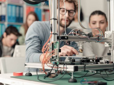 Erkek ve dişi mühendislik öğrencileri bir 3d printerlere harcama maddeler laboratuarı, teknoloji ve öğrenme kavramı kullanarak