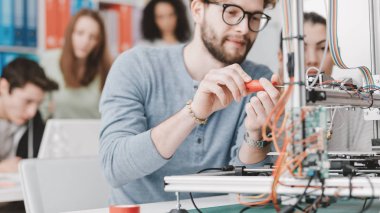 Mühendisliği öğrencileri, laboratuvarda bir 3d yazıcı kullanarak bir öğrenci bir tornavida kullanarak