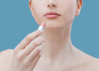 Genç güzel kadın bir pembe ruj dudakları üzerinde uygulamak Cilt Bakımı ve makyaj kavramı