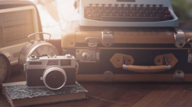 Bir masa üzerine Vintage nesneleri: bavul, fotoğraf makinesi, radyo, daktilo ve korku masa saati