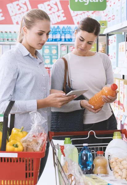 幸せ女性の友人は 一緒にスーパーで買い物 検索製品があり デジタル タブレットを接続しています — ストック写真