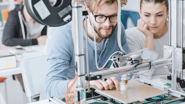 Engineering students using a 3D printer in the lab, learning and technology concept