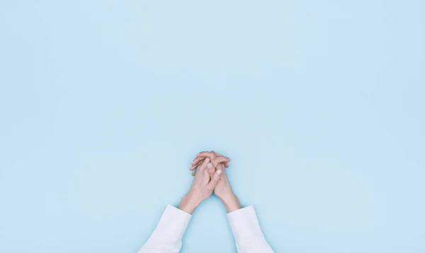 Female hands clasped on light blue background and copy space