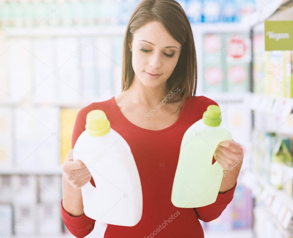 Woman shopping at the supermarket and comparing detergent products, she is reading labels