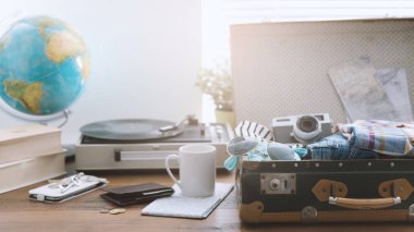 Tatile çıkmadan önce onun Bagaj paketleme traveler: Giysi, fotoğraf makinesi ve vintage rekor çalar, seyahat ve retro canlanma kavramı ile açık vintage çanta