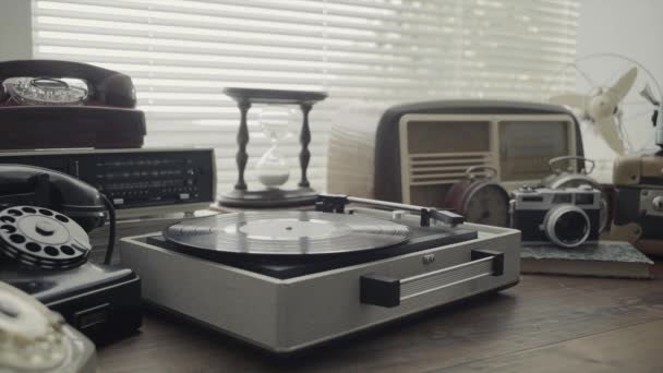 Man playing a vinyl record on a vintage record player and collection of old objects on a table, retro revival and nostalgia concept