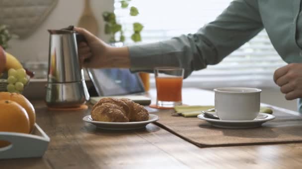 朝食を家庭で有すると萌香鍋を使用してカップに熱いコーヒーを注ぐ女性 — ストック動画