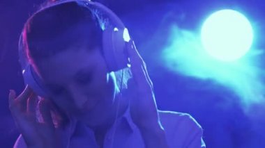 Güzel kadın diskoda: kulaklık, müzik ve dans giyiyor