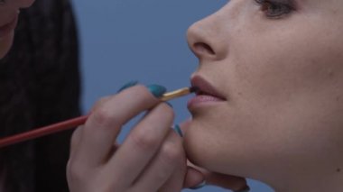 Profesyonel bir fırça, güzellik ve kozmetik kavramı kullanarak modelin dudaklarından ruj uygulama sanatçı makyaj