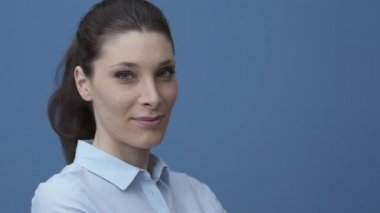 Poz ve kameraya bakarak genç iş kadını gülümseyen, bir tişört giyiyor