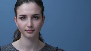 Genç güzel kız kamera ve gülümseyen, mavi arka plan üzerinde poz