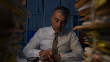 İşadamı, iş ile aşırı yüklenmiş office masada oturuyor ve gece geç saatlerde mesai, masasının paprwork, dolly atış dolu