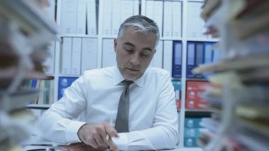 İş yürütme çalışması ile bunalmış, o evrak ve dosyalardan, dolly atış yığınları vardır