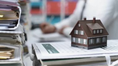 Bir yığın evrak ve gerçek emlakçı masa başında çalışma modeli ev: gayrimenkul, mortgage kredisi ve ekonomi kavramı
