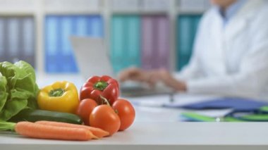 Ofiste çalışan profesyonel beslenme uzmanı o bağlanma ve bir dizüstü bilgisayar, taze sağlıklı sebze ön Tarih yazarak