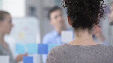 Arka planda çalışan office ve iş takım işçisi kadın ofis gülümseyen genç, o döner ve kameraya görünüyor
