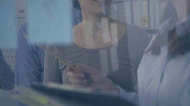 Une jeune équipe d'affaires réunie au bureau et travaillant ensemble, deux femmes discutent au premier plan et vérifient la paperasserie, le travail d'équipe et le concept de démarrage 