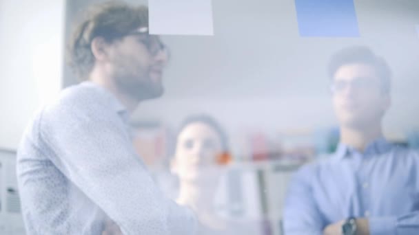 Jeune équipe créative d'affaires se réunissant au bureau et discutant d'un projet ensemble, un homme pointe du doigt les notes collantes, le travail d'équipe et le concept de démarrage 