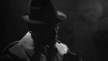 Bir sigara Noir casus film karakteri onun trençkot yaka uyum sağlıyor.