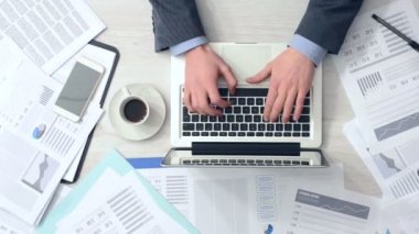 Ofis Masası diz üstü ile çalışan ve bir sürü evrak ve finansal raporlar, eller üstten görünüm tarafından çevrili kahve içme işadamı