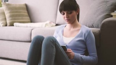 Katta ve cep telefonu ile mesaj oturan genç kadın, evde, sosyal ağ ve gülen kız