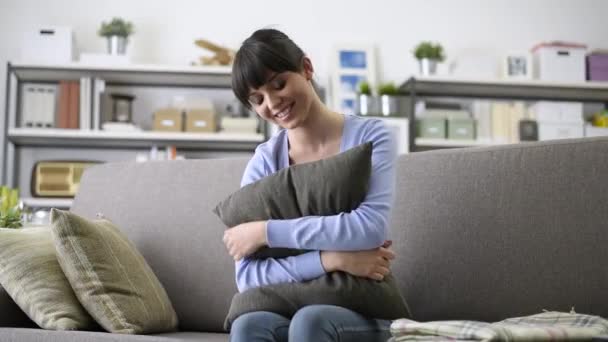 微笑的年轻女子在家里玩 放松在沙发上 她扔在相机的枕头 — 图库视频影像