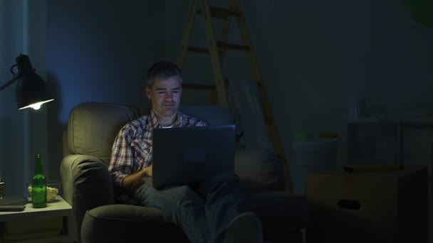 El hombre que conecta con un ordenador portátil en casa — Vídeo de stock