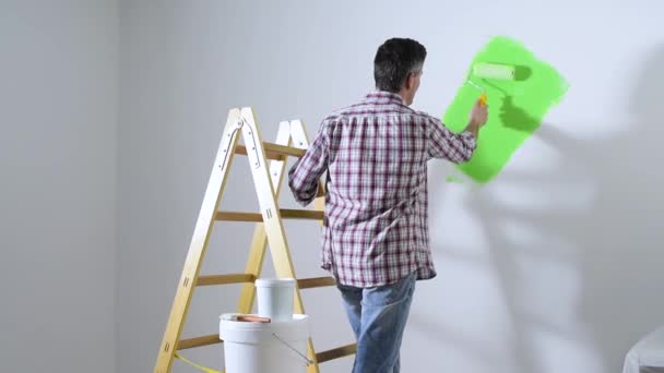Человек рисует внутренние стены дома — стоковое видео