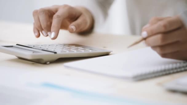 Mujer usando una calculadora y escribiendo notas — Vídeos de Stock