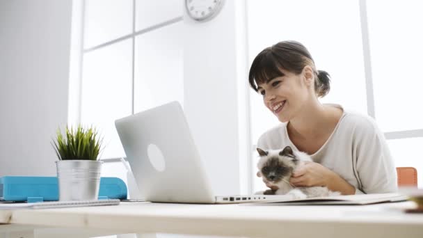 Smiling woman social networking and cuddling her cat — Stock Video