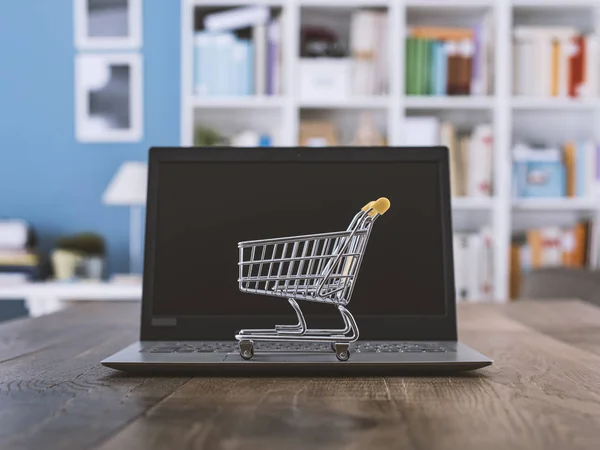 Miniatur-Einkaufswagen und Laptop auf dem Schreibtisch — Stockfoto