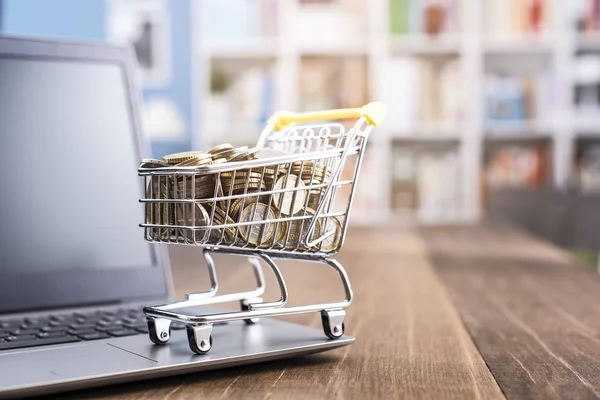 Carro de compras lleno de dinero y portátil — Foto de Stock