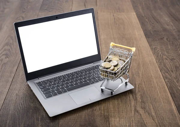 Nákupní košík plný peněz a laptop — Stock fotografie